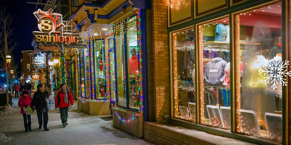 Downtown Breckenridge shops lit up at night with shoppers on sidewalk